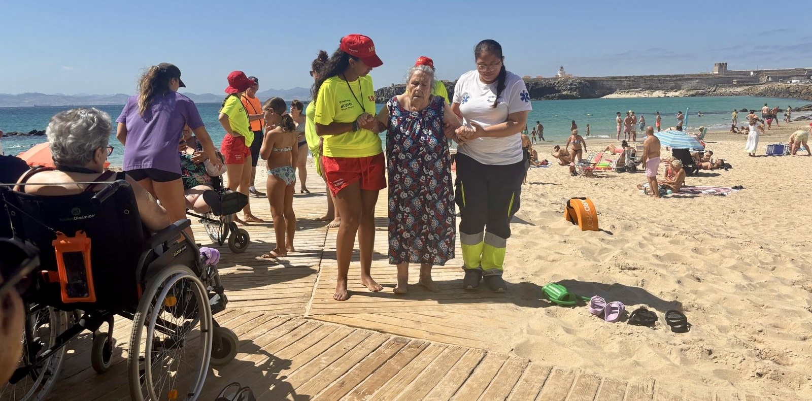 Personal del servicio de socorro y personal del geriátrico ayudan a una mujer a regresar de la orilla/TAD